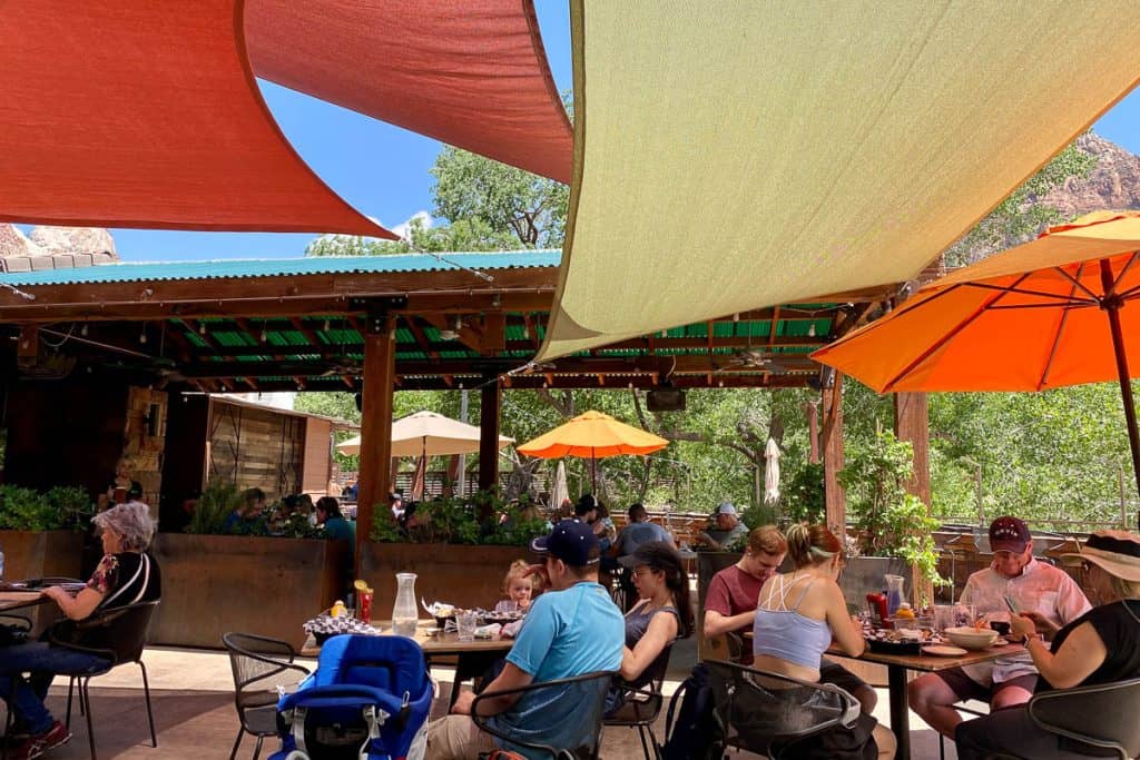 Diners sitting outside at tables under fabric canopies at Zion Brew Pub.
