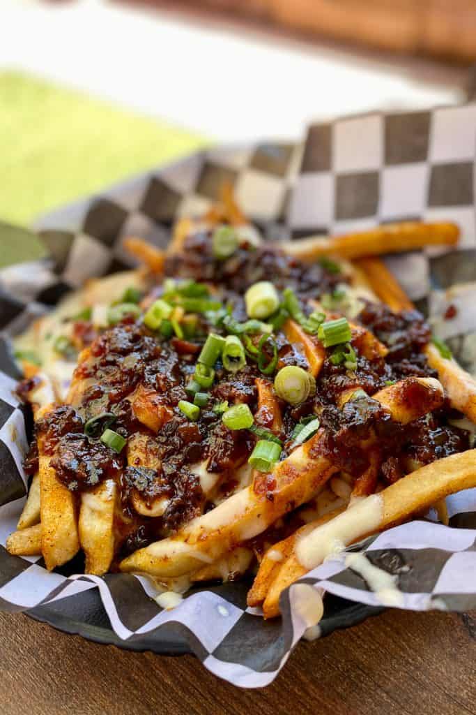 Pub fries topped with bacon jam, beer cheese, and green onions.