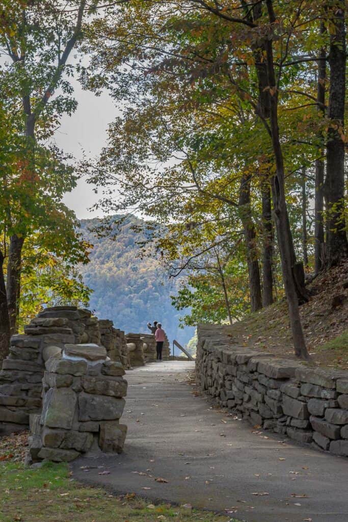 Paved walkway between stone walls leading to overlook at Hawks Nest State Park.