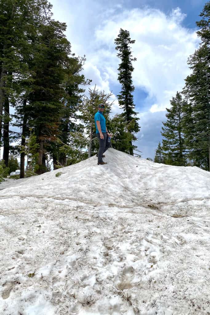 Hiker standing on top of muddy, compacted bank of snow.