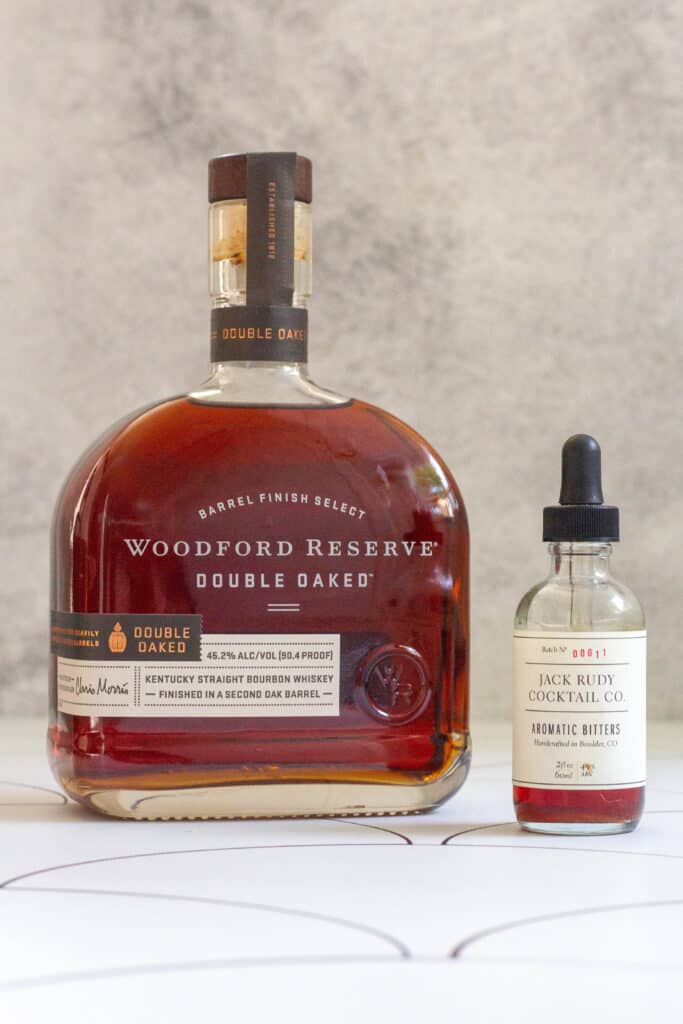 Bottle of Woodford Reserve bourbon next to small bottle of aromatic bitters.