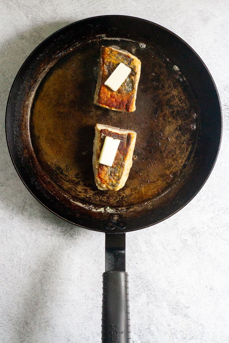 fillets in a hot pan topped with butter knobs.