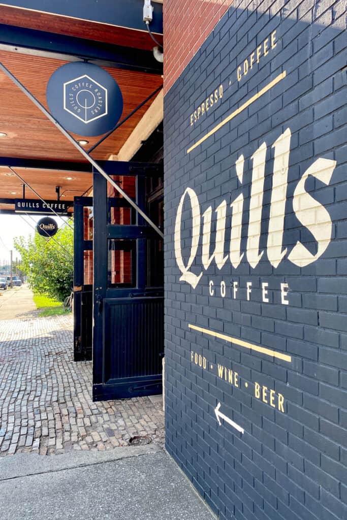 Quills Coffee painted on black brick wall next to entrance.