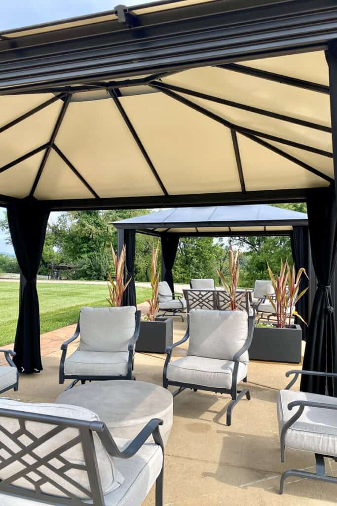 Cabana with chairs and black curtains tied at corners.