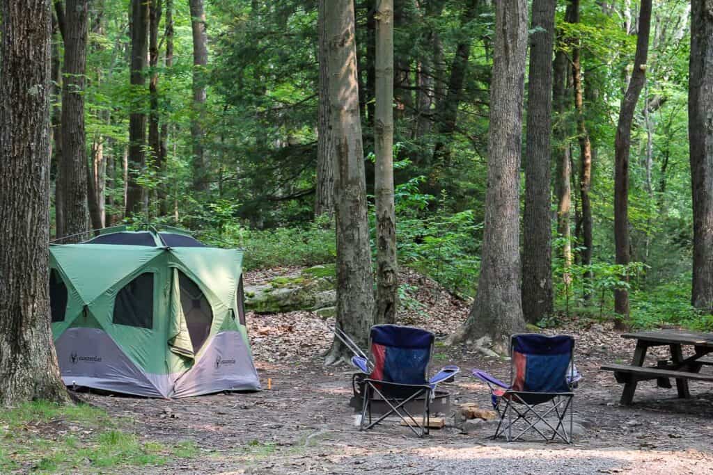 Tent and camp chairs at campsite.