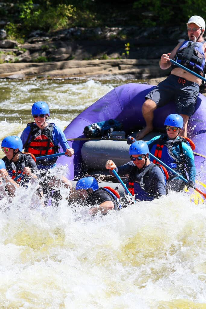 Rafters navigating whitewater on Gauley River, with boat tipping downwards into the spray.