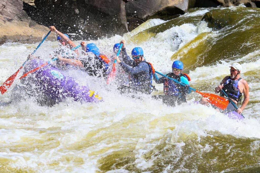 Rafters navigating whitewater on Gauley River, with lots of spray enveloping the boat.