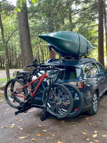 Kayaks loaded on roof rack and bikes loaded on back of car.
