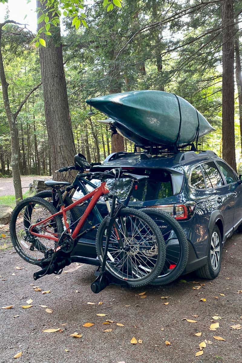 Kayaks loaded on roof rack and bikes loaded on back of car.