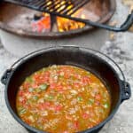 Dutch oven full of campfire taco soup with campfire in background.
