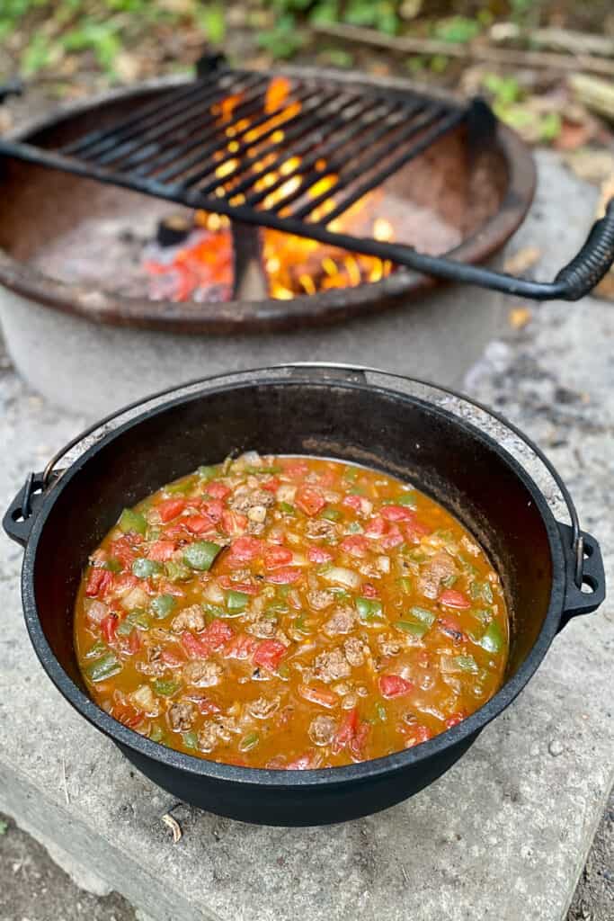 Dutch oven full of campfire taco soup with campfire in background.