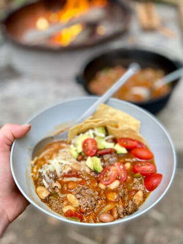 Bowl of campfire taco soup with fresh tomatoes, avocados, cheese and chips on top.