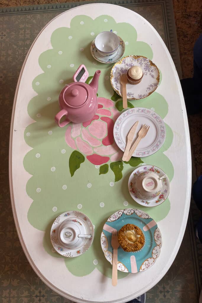 Pumpkin cream cheese muffin, caramel pumpkin cupcake, pot of tea, and three teacups on saucers.