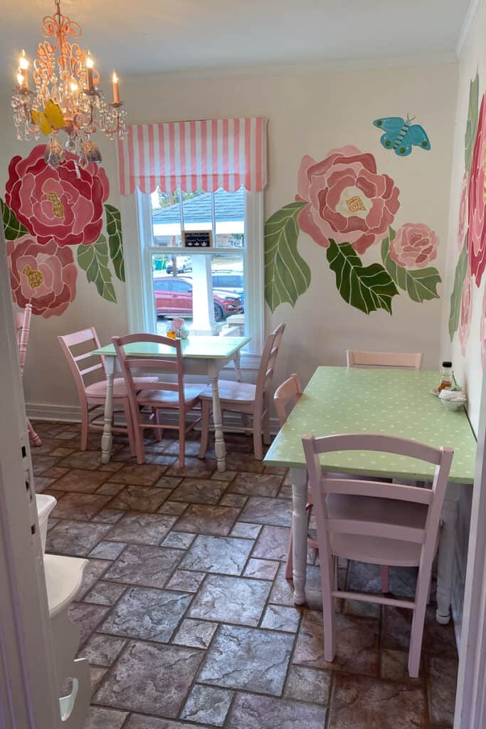 Dining room with large pink roses painted on walls and pink and green furnishings.