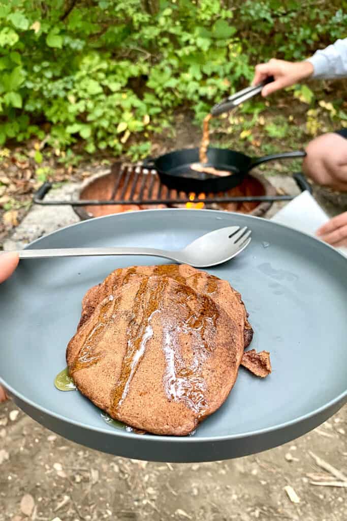 Plate of pancakes with campfire in background.
