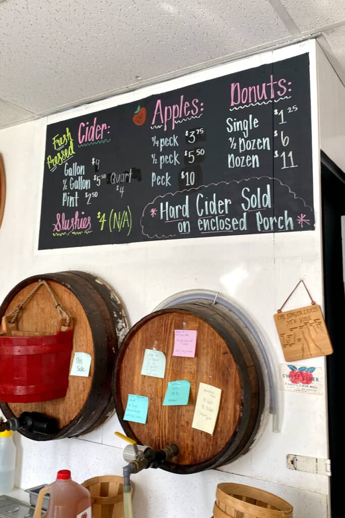 Chalkboard with pricing for apple cider, donuts, apples, and slushies at Wagers Cider Mill.