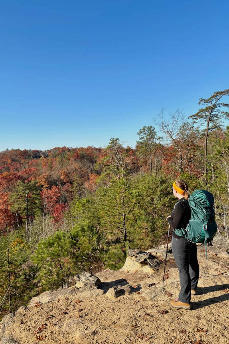 Woman with Osprey Eja pack standing at forest overlook.