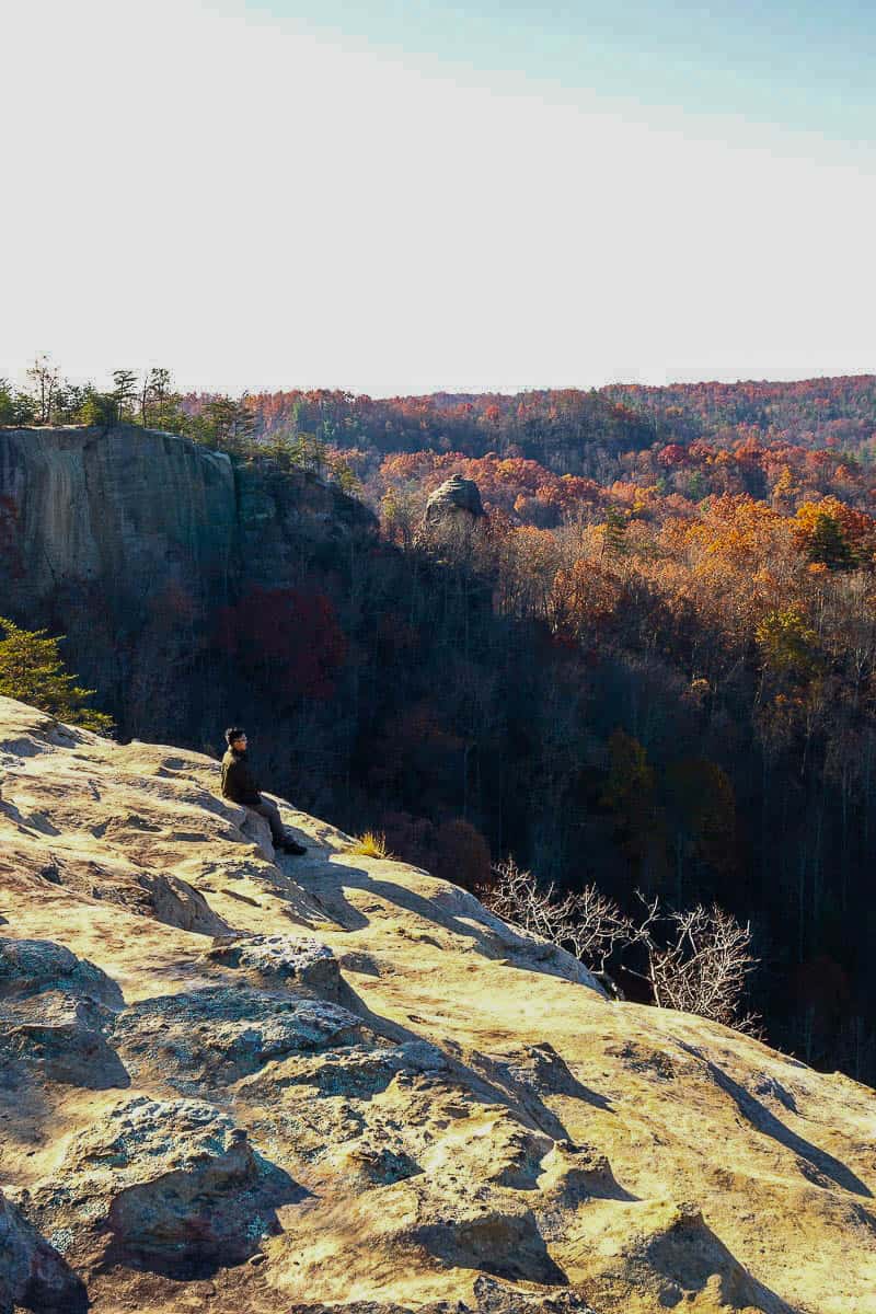 Man sitting on rocky ledge of Auxier Ridge viewing valley below.
