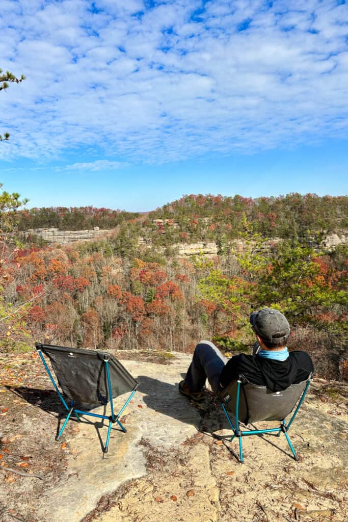 Hiker resting in camp chair at scenic overlook in Red River Gorge.