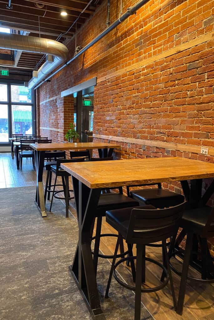 Indoor dining area with tables lining brick wall.