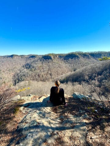 Woman seated at rocky overlook viewing gorge.