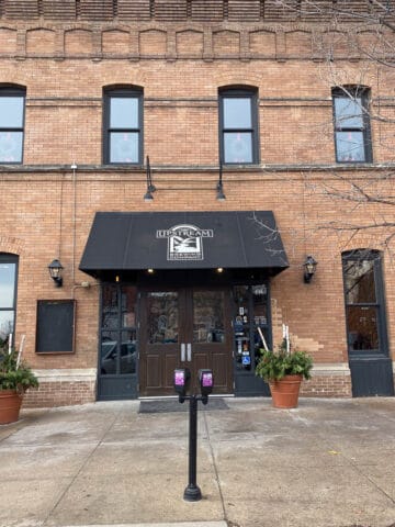 Double door entrance in brick building with awning labeled "Upstream Brewing Company."