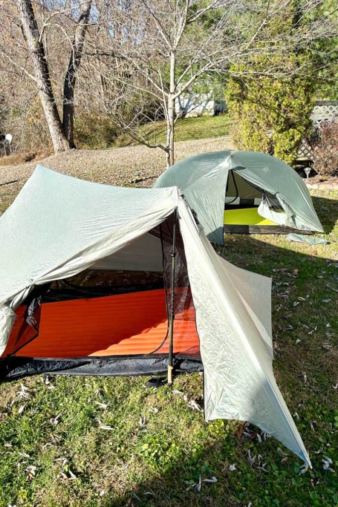 Two ultralight tents pitched in yard, with flaps pulled back and sleeping pads inside.