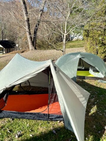 Two ultralight tents pitched in yard with flap pulled open to show sleeping pads inside.