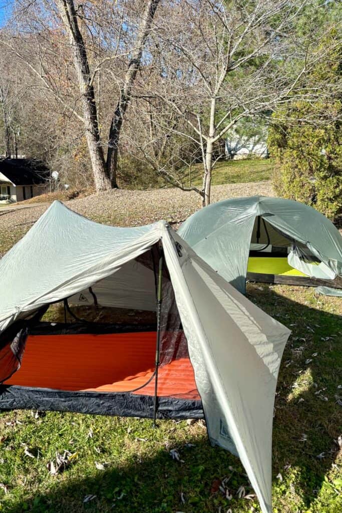 Two ultralight tents pitched in yard with flap pulled open to show sleeping pads inside.