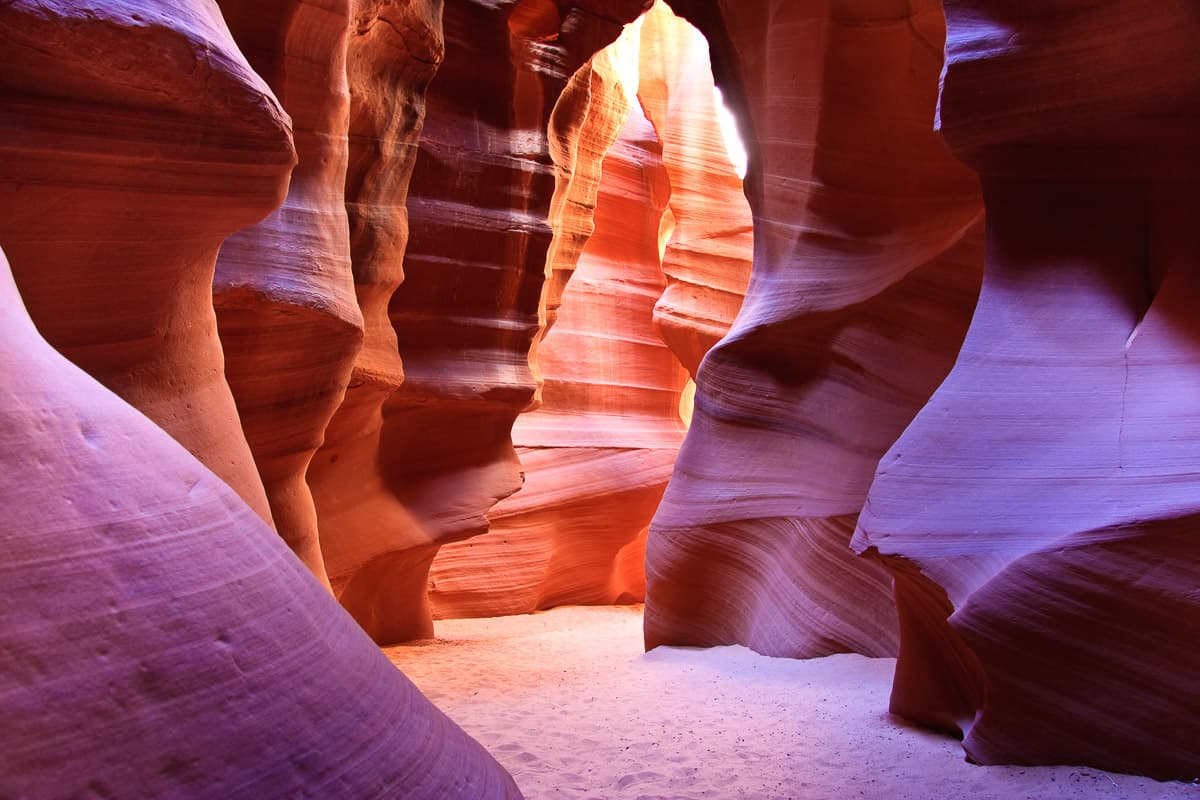Antelope Canyon, a slot canyon with sandy floor and sandstone walls with undulating patterns.