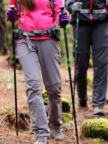 Two hikers on trail with trekking poles, hiking shoes and backpacks.