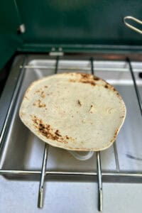 Tortilla being warmed on camp stove.