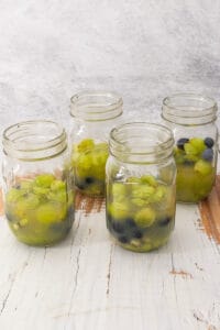 Jars with fruit and halfway filled with brandy and juice.