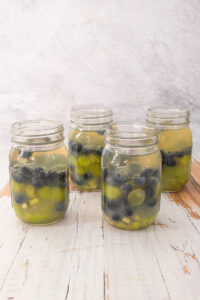 Jars filled with fruit, brandy, juice and white wine to make summer camping sangria.