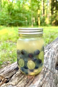 Jar of summer camping sangria filled with fruit, brandy, juice and white wine.