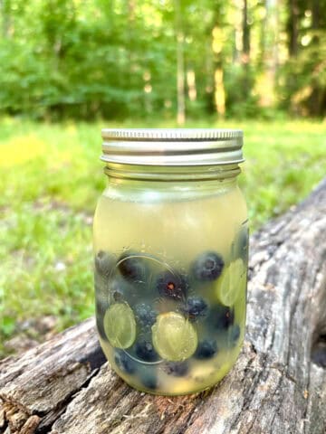 Jar of summer camping sangria filled with fruit, brandy, juice and white wine.