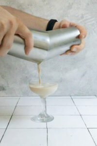Straining mocha martini from cocktail shaker into glass.