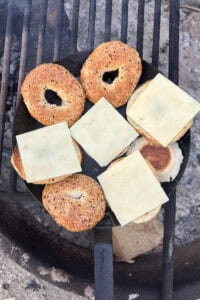 Bagel halves with sliced cheese in skillet.