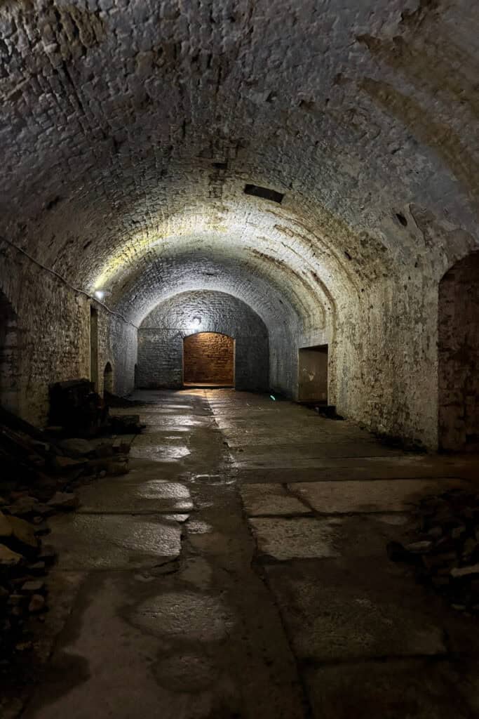 Stone lined room with arched ceiling and dim lighting seen o a Cincinnati underground brewery tour.