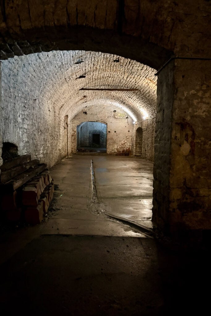 Well-lit stone-lined cavernous space seen on a Cincinnati underground brewery tour.