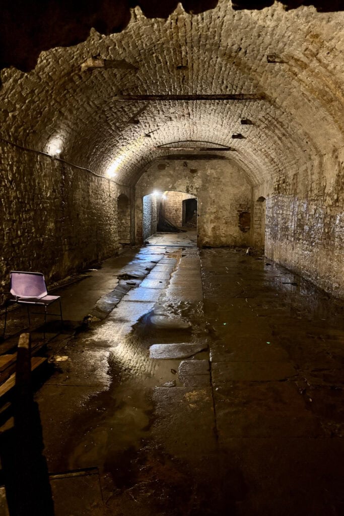 Stone-lined cavernous rooms with arched ceilings and damp floors seen on a Cincinnati underground brewery tour.