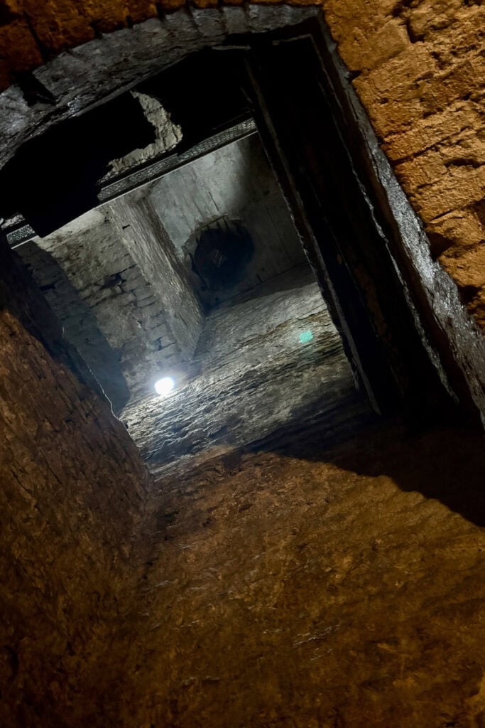 View from ground level up through two stories of underground stone-lined spaces seen on a Cincinnati underground brewery tour.