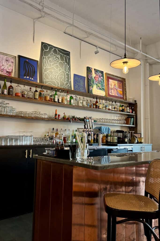 Bar area with drink ingredients and art display.