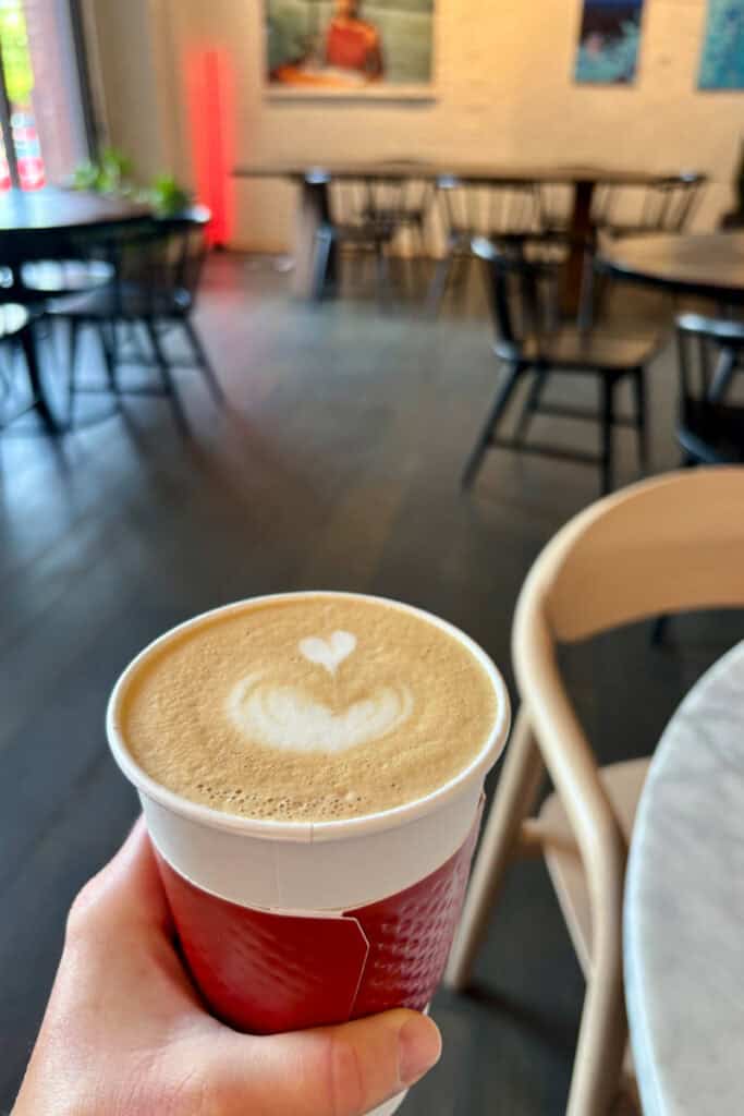 Latte in disposable cup with heart design in the foam on top.