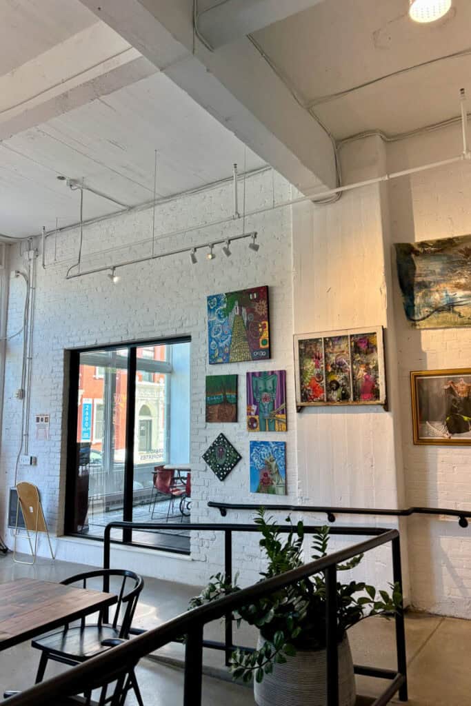 Paintings displayed on white brick wall at Redtree Coffee.
