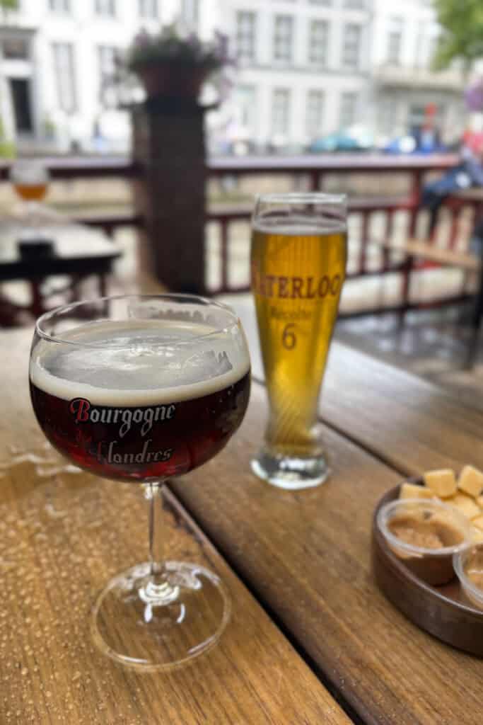 Glasses of beer on rain-sprinkled table in outdoor dining area at Brewery Bourgogne des Flandres.