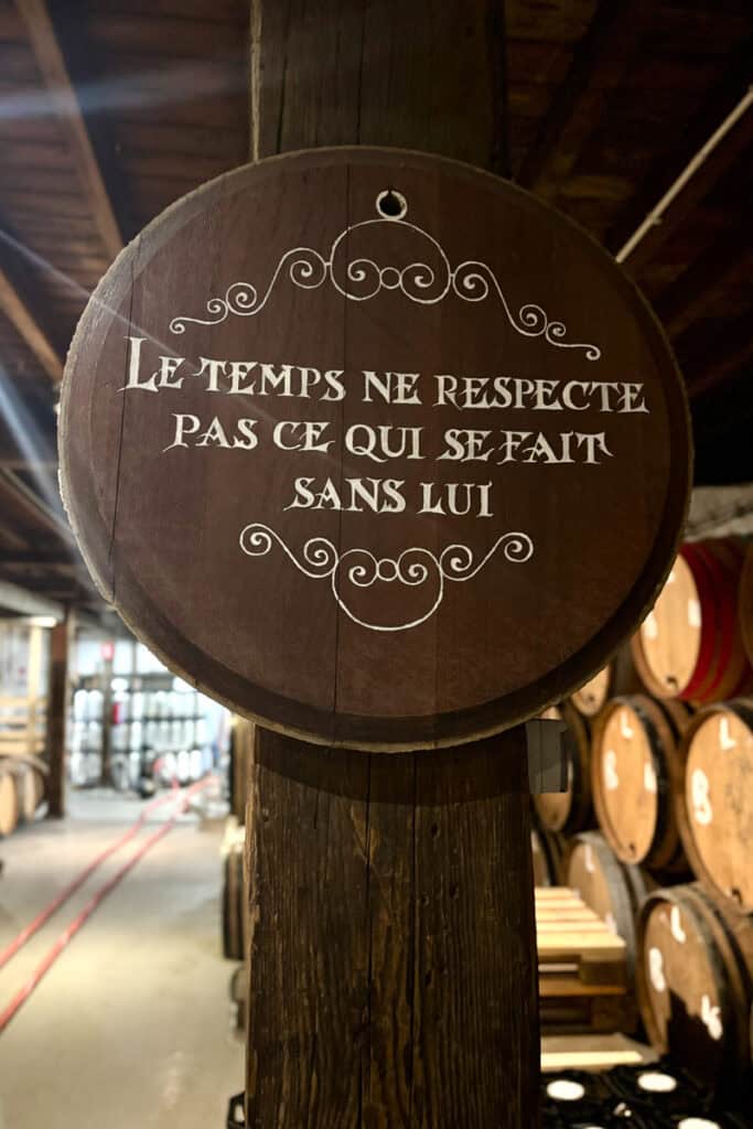 Wooden sign bearing the French words "le temps ne respecte pas ce qui se fait sans lui," or "time does not respect what is done without it."