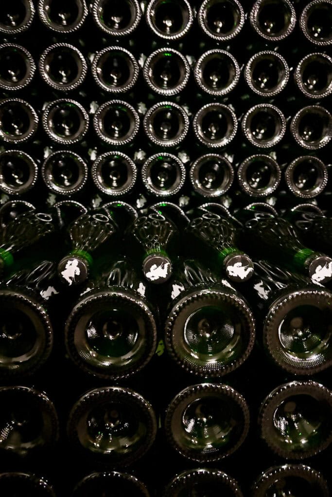 Dozens of beer bottles laid horizontally with bottoms facing out, alternated with one row with bottle caps facing out.