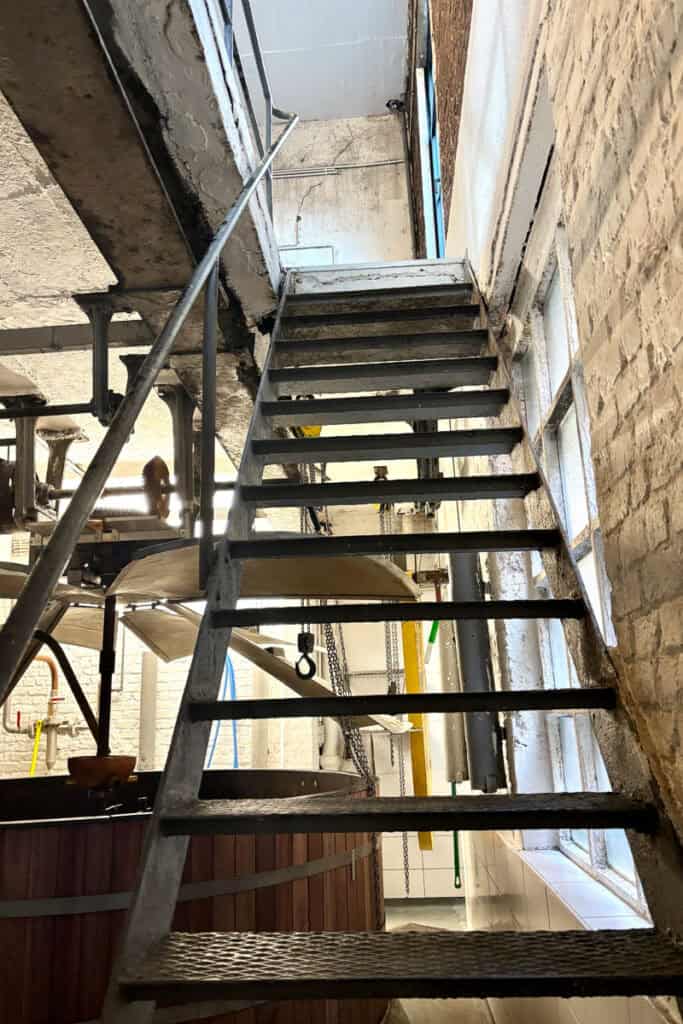 Metal staircase rising above wooden beer vat.