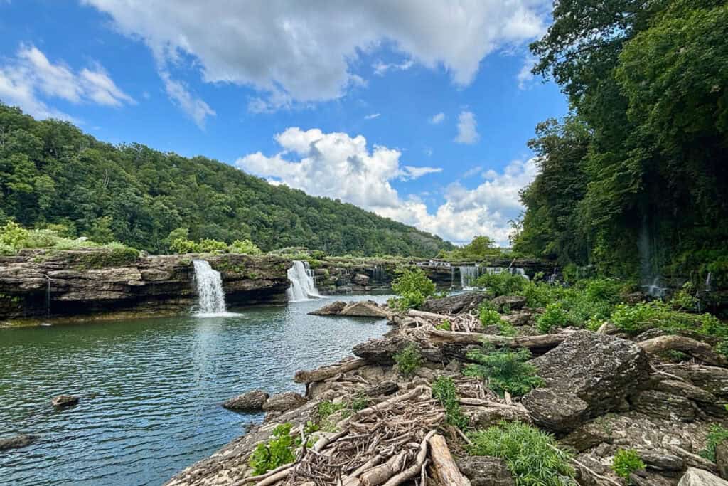 Multiple waterfalls coming off a long low rock cliff.